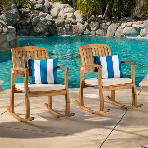 two wooden rocking chairs sitting next to a pool