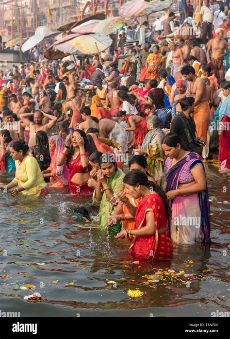 Hindu worshippers perform ritual bath and puja prayers in the River Ganges, Varanasi, India ...