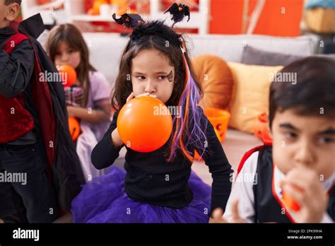 Group of kids wearing halloween costume inflating balloons at home ...