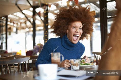 Woman laughing while dining in cafe with friend — women, afro - Stock ...