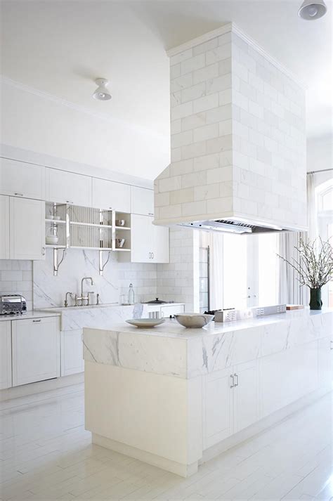 a large kitchen with white cabinets and marble counter tops, along with an island in the middle