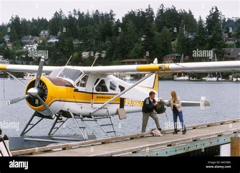 Kenmore Air seaplane at dock and pilot helping passenger with baggage Friday Harbor San Juan ...