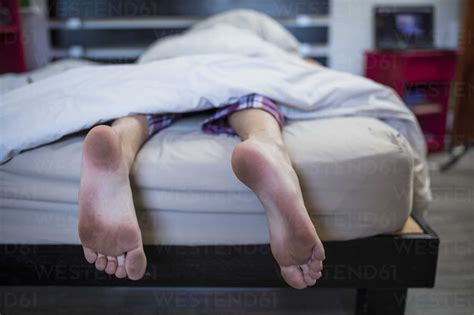 Dirty feet of boy lying in bed stock photo