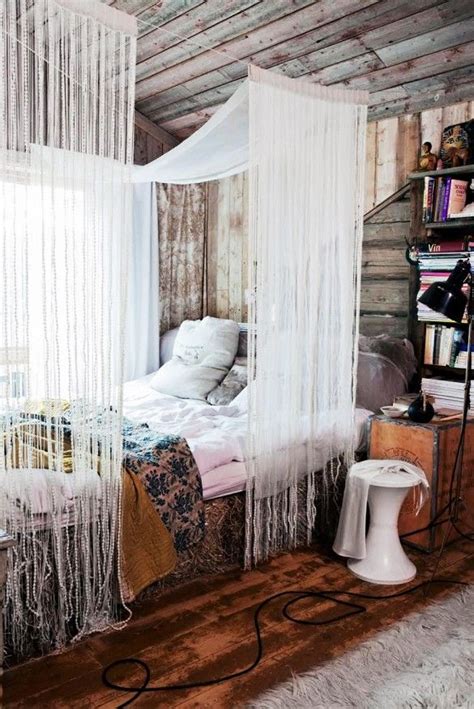 a bedroom with a bed, rugs and white curtains hanging from the ceiling ...