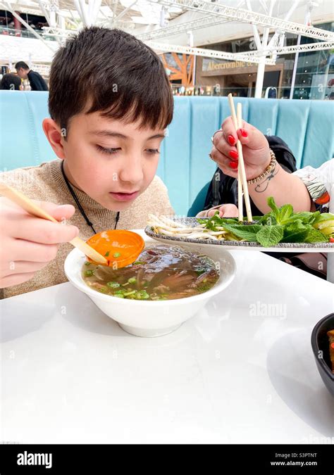 A boy eating a bowl of Vietnamese pho in a food court Stock Photo - Alamy