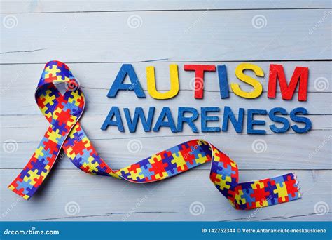 World Autism Awareness and Pride Day or Month with Puzzle Pattern Ribbon on Blue Wooden ...