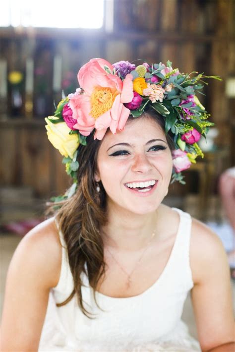 a woman with flowers in her hair smiles at the camera while wearing a ...