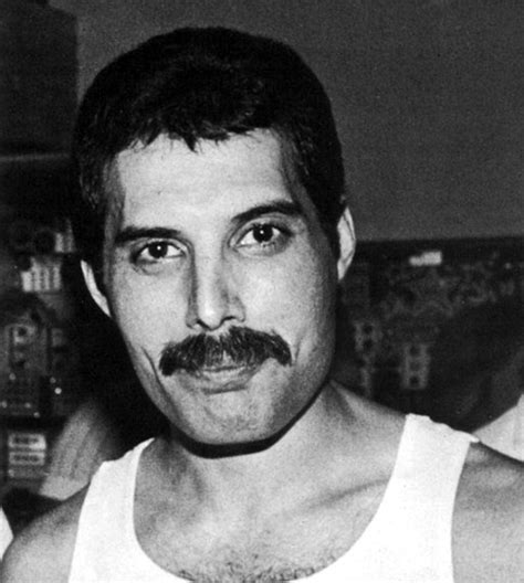 black and white photograph of a man with a moustache on his face wearing a tank top