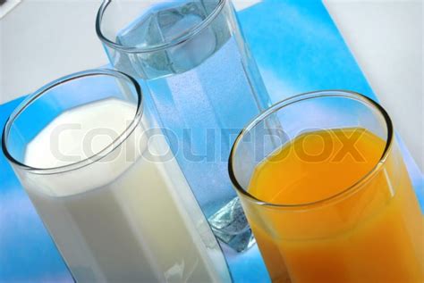 Three glasses with water, milk and juice closeup | Stock Photo | Colourbox