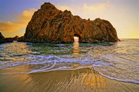 the sun is setting behind an arch in the rock