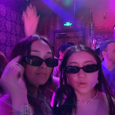 two women wearing sunglasses are posing for the camera at a party with other people in the ...
