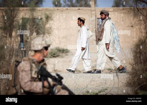 Afghan men travel to the Garmsir Agricultural High School to vote in district community council ...