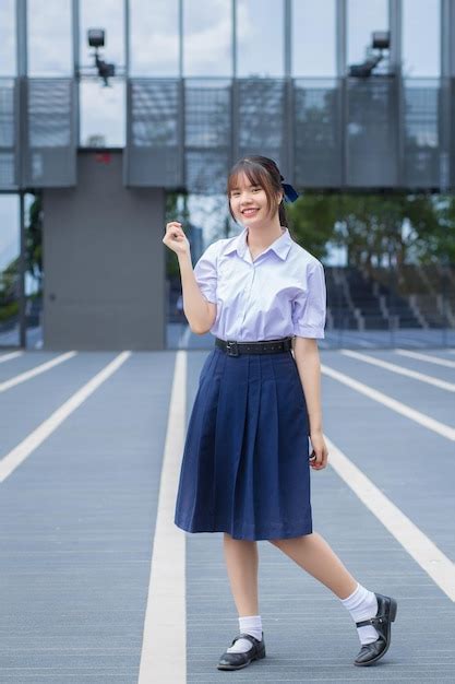 Premium Photo | Cute high school asian student girl in school uniform stands and smiles happily ...