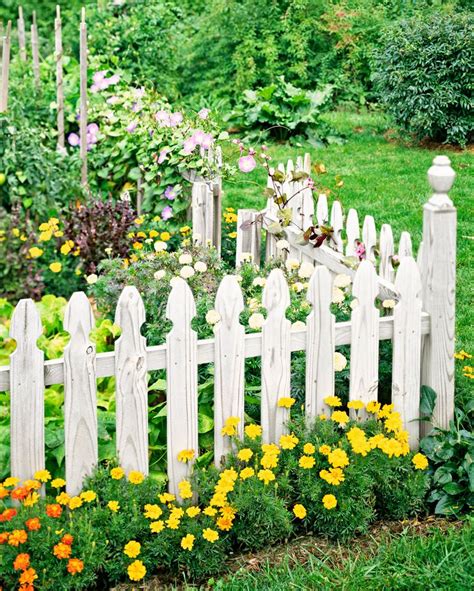 a white picket fence surrounded by flowers and greenery