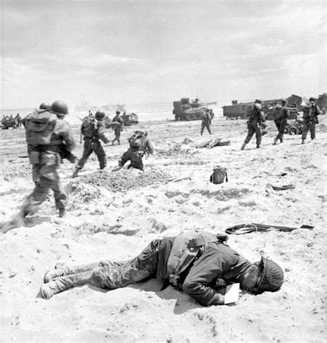 U.S. Army troops forge ahead on Omaha Beach past a fallen comrade, killed by enemy German fire ...