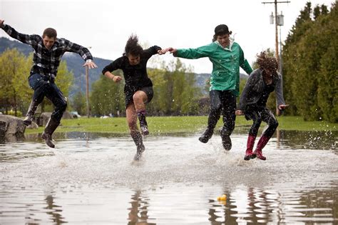 Young adults jump and splash in a large puddle stock photo