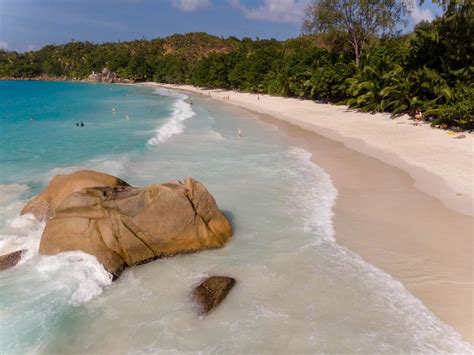 Waves of the blue Indian Ocean break at a granite rock next to Anse ...