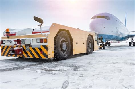 Premium Photo | Tow tractor pushes the passenger aircraft at the cold winter airport apron