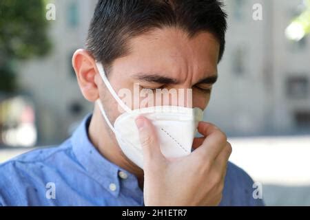 A man sneezing into protective mask against transmissible infectious diseases and as protection ...