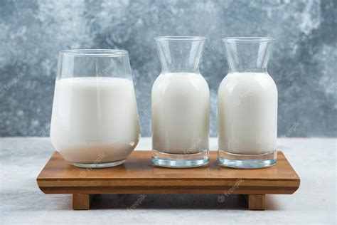 Free Photo | A glass cup of milk and two glasses jar of milk on a wooden small desk.