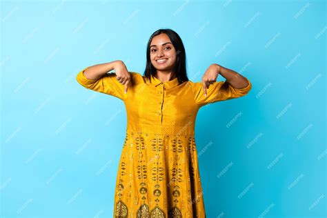 Premium Photo | Indian lady wearing traditional dress pointing fingers down blue background