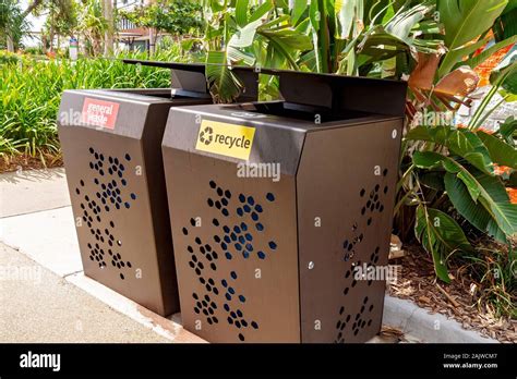 General waste and recycle rubbish bins beside a garden in a public outdoor recreational park ...