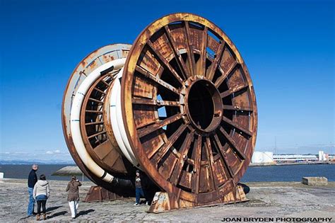 two people standing next to large wooden wheels