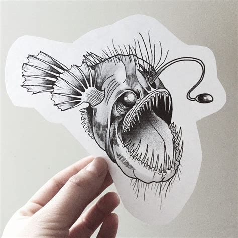 a hand holding up a sticker with an image of a fish in it's mouth