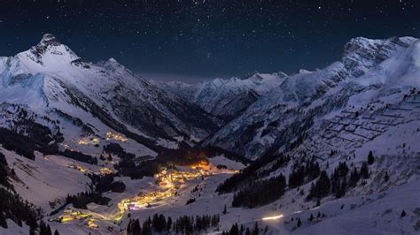 the night sky is full of stars and lights above snow covered mountains ...