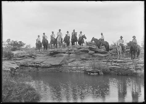 A group of mounted cowboys lined up behind a waterhole in Blanco Canyon ...