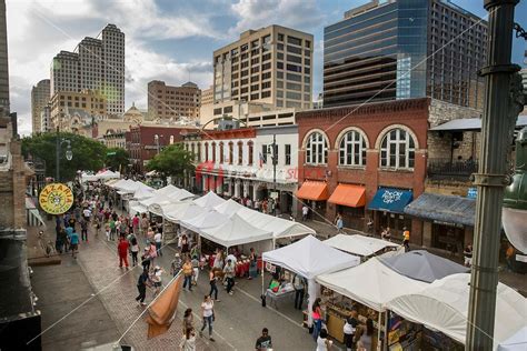 an outdoor market with tents and people walking down the street in front of tall buildings