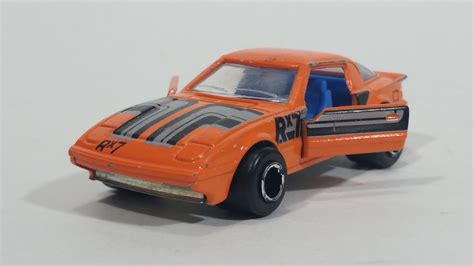 an orange toy car with black stripes on the front and back sides, sitting on a white surface