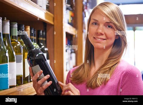Woman Choosing Bottle Of Red Wine In Supermarket Stock Photo - Alamy