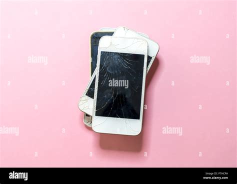 pile of old broken mobile phones with pink background Stock Photo - Alamy