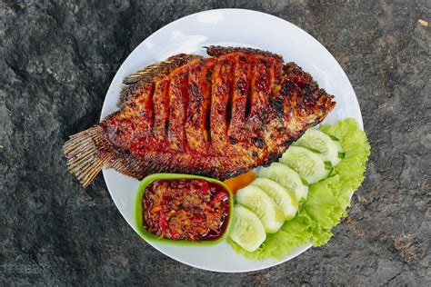 Delicious grilled tilapia from indonesia with rice, tempeh, vegetables, and chilli sauce in ...