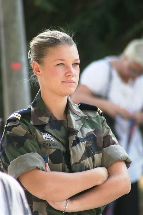 a woman in uniform is standing with her arms crossed and looking off to the side