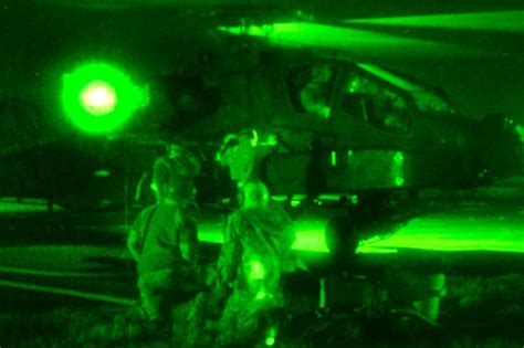 As seen through a night-vision device, soldiers refuel AH-64 Apache ...