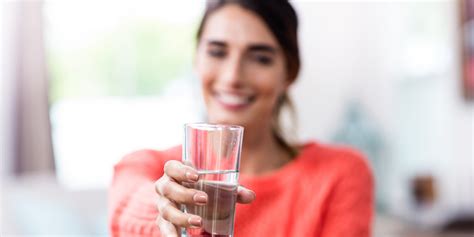 Young woman showing drinking glass with water - Ask The Scientists