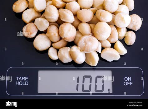 Macadamia nuts on digital scale displaying 100 gram Stock Photo - Alamy