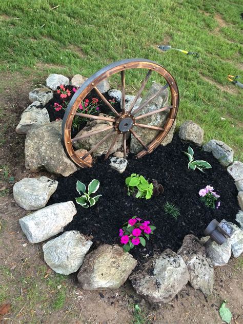 an old wheel is sitting in the middle of some rocks and dirt with ...