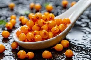 Ripe fruits of sea buckthorn with drops of water on a black background. View from above ...