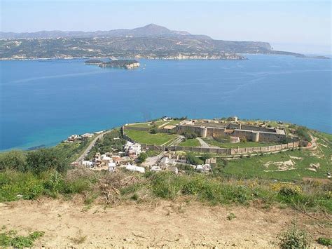 an aerial view of a small town by the water and hills in the distance,