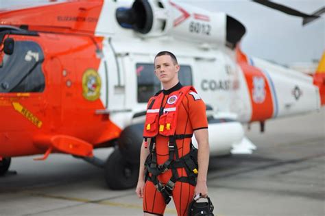 a man in an orange life jacket standing next to a helicopter