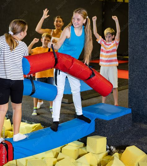 Smiling children having funny wrestling by inflatable logs in indoor ...