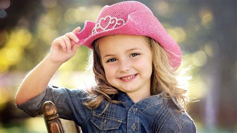 Cute Smiley Little Girl Is Wearing Jeans Shirt And Pink Hat Sitting On ...