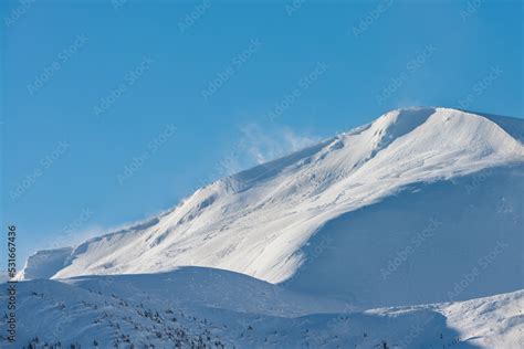 Snow-covered mountain top. The wind rises the snow on the mountain ...