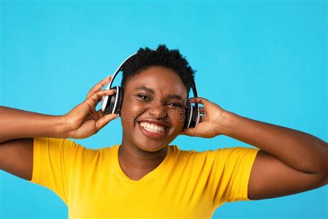 Black Woman Wearing Headphones Listening To Music Over Blue Background ...