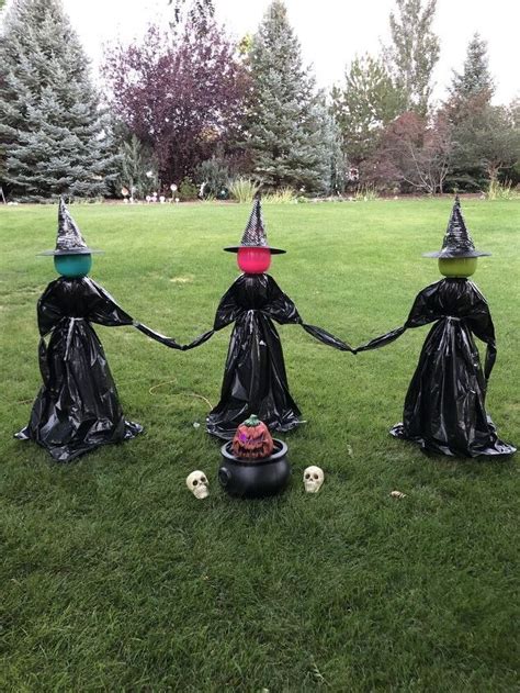 three plastic witches holding hands in the grass