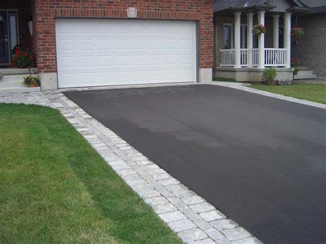 an asphalt driveway in front of a brick house