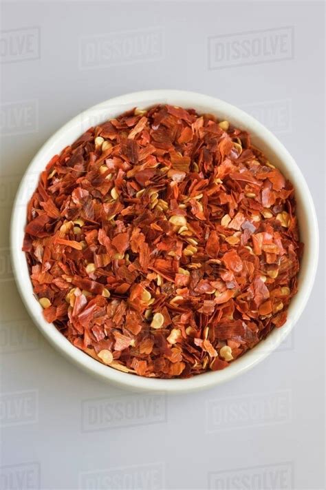 Dried chilli flakes in small white bowl - Stock Photo - Dissolve